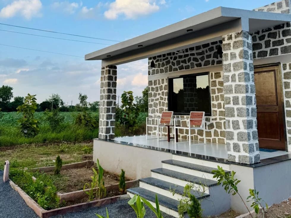 Stone cottage at Upvan Jawai with a green field and blue sky behind it