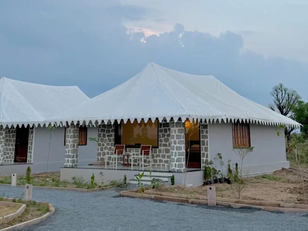 A tented cottage at Upvan Jawai in daylight, granite walls under a white canvas roof