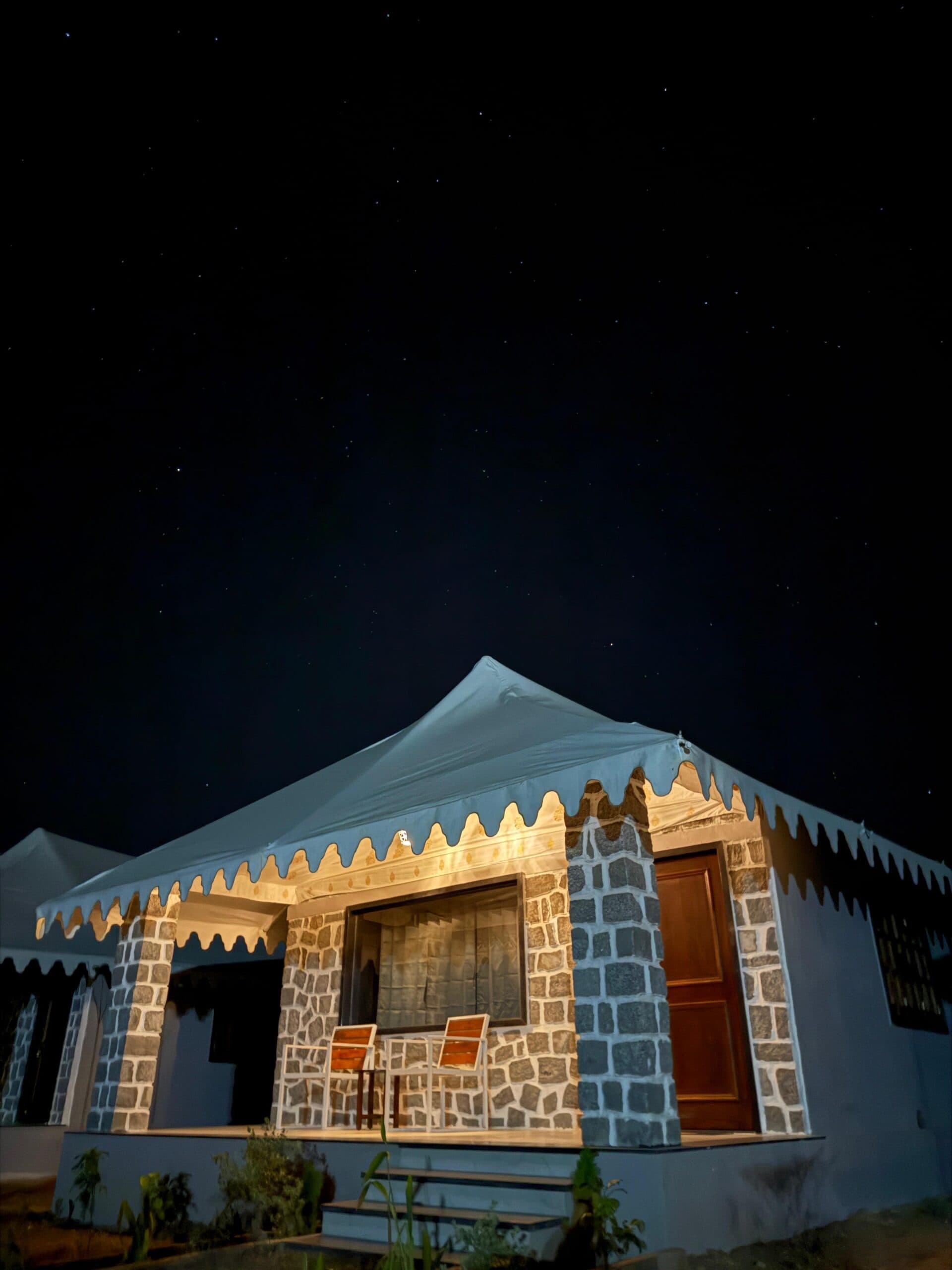 A tented cottage glowing from inside after dark